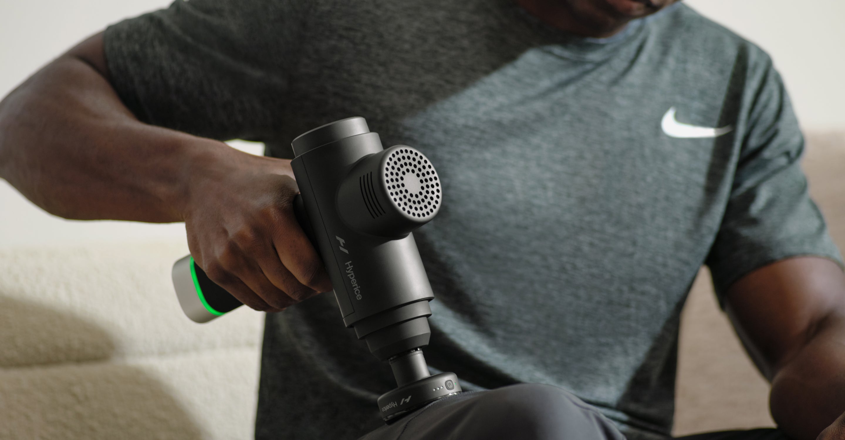 Person holding a hypervolt 2 pro with a heated head on a blurred background