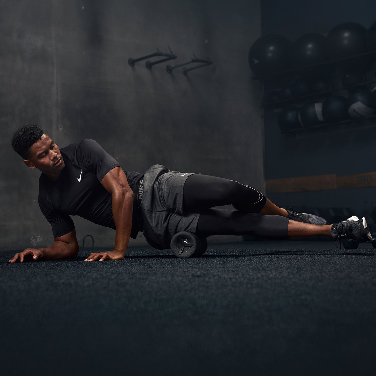 Man using a Vyper 3 roller for self-massage in a gym setting