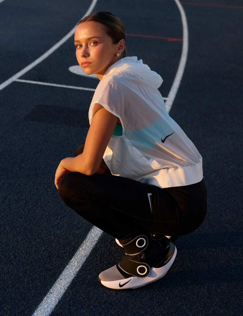 Persona in abbigliamento sportivo con le Hyperboots Nike x Hyperice, in posa su una pista