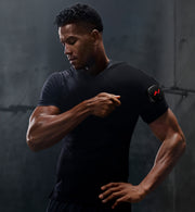 Man wearing a black t-shirt adjusting his venom 2 shoulder against a dark background