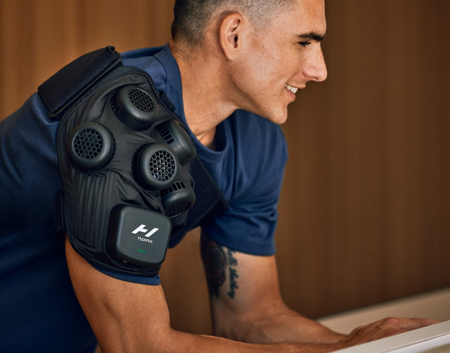 Man in home wearing Hyperice X Shoulder contrast therapy recovery device.