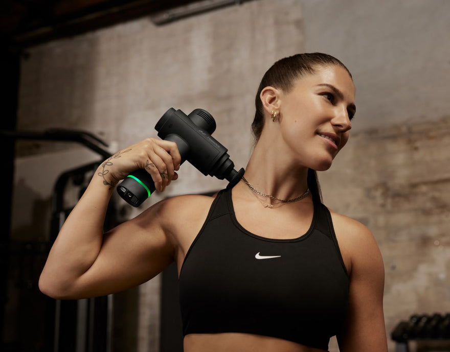 Woman using Hypervolt 2 on neck while in gym.