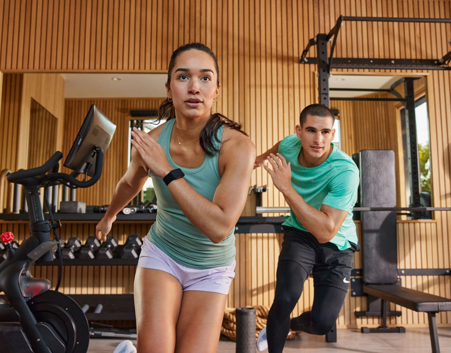 Man and woman in timber slated gym doing cross jumps.