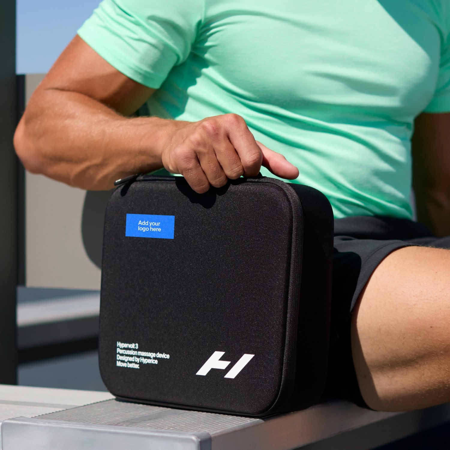 homme sur un banc tenant l'étui de transport Hypervolt 3