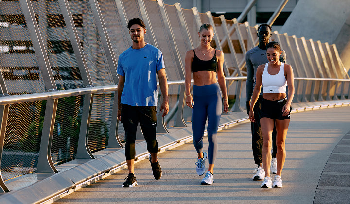 Four people walking on a bridge in athletic wear