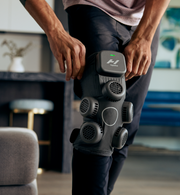 Person using a Hyperice X contrast device on their leg in a home setting