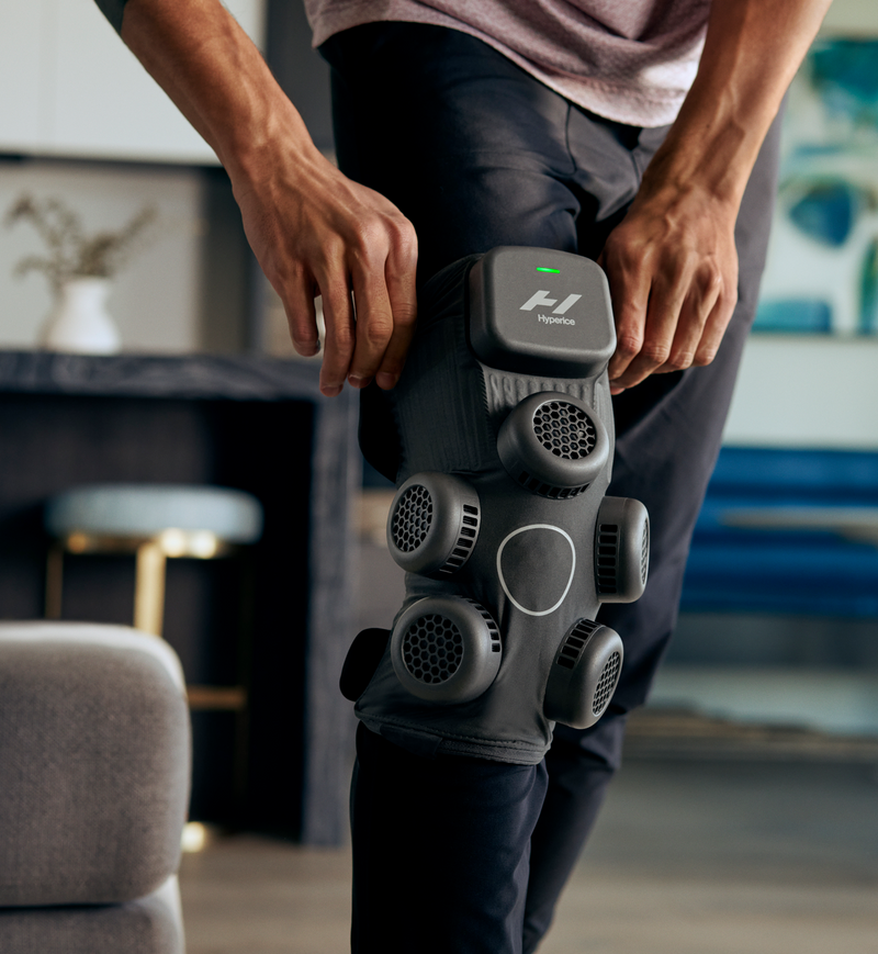 Person using a Hyperice X contrast device on their leg in a home setting