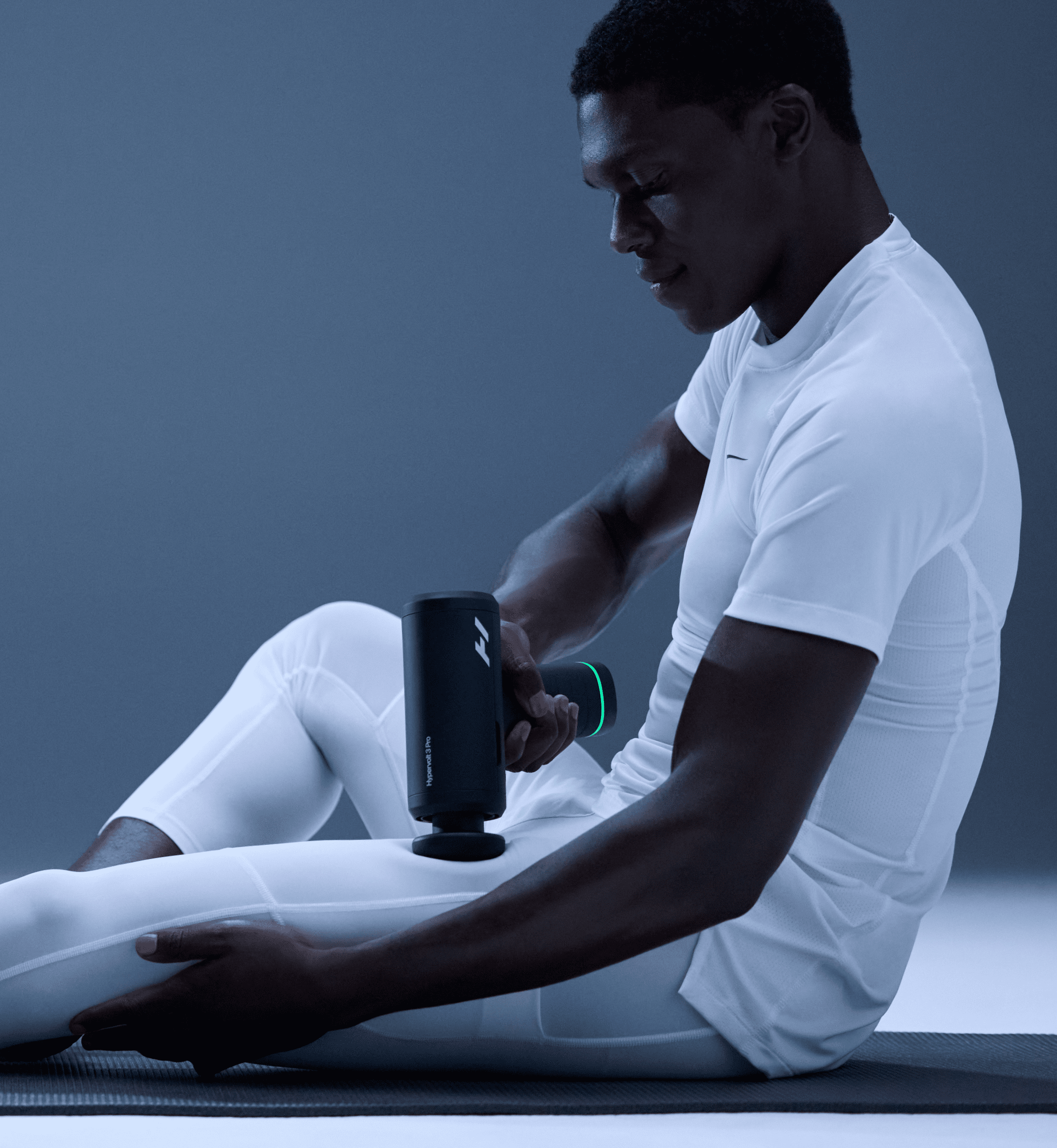 Man using a Hypervolt 3 Pro massage gun on his leg with a dark background