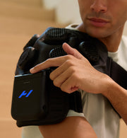 side shot of a person adjusting the control unit of the hyperice x 2 shoulder device
