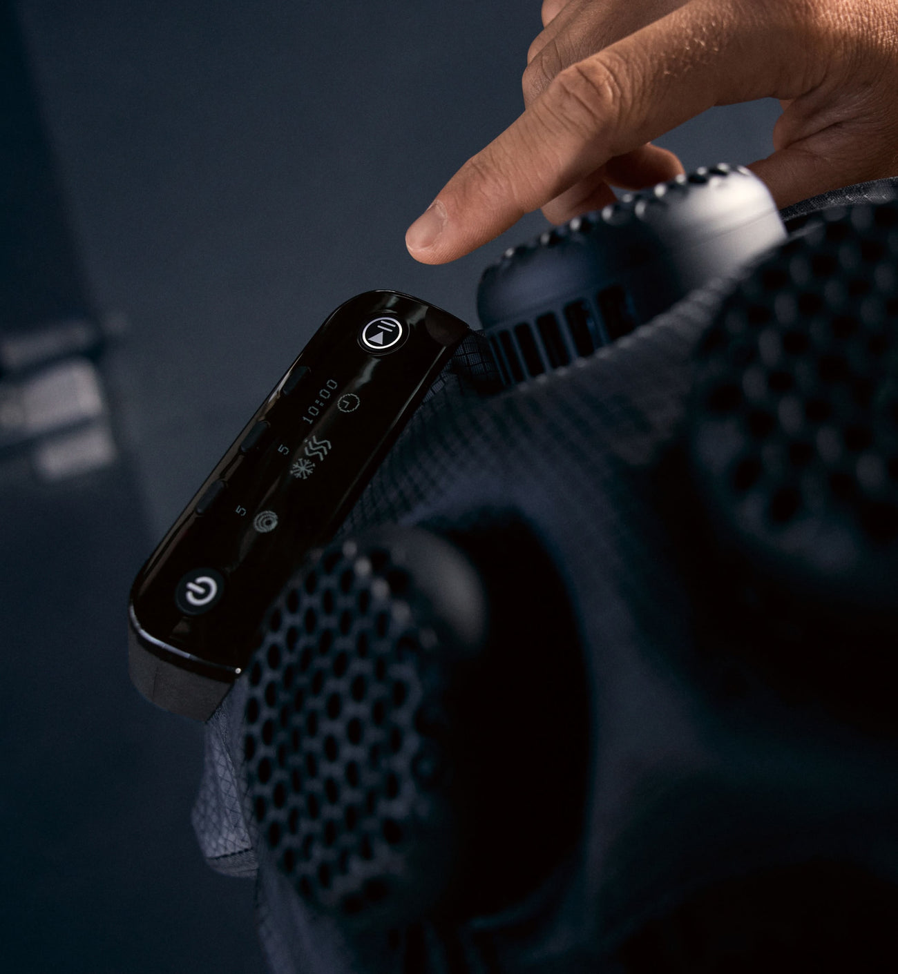 close up shot of a person adjusting the control unit on a hyperice x 2 shoulder