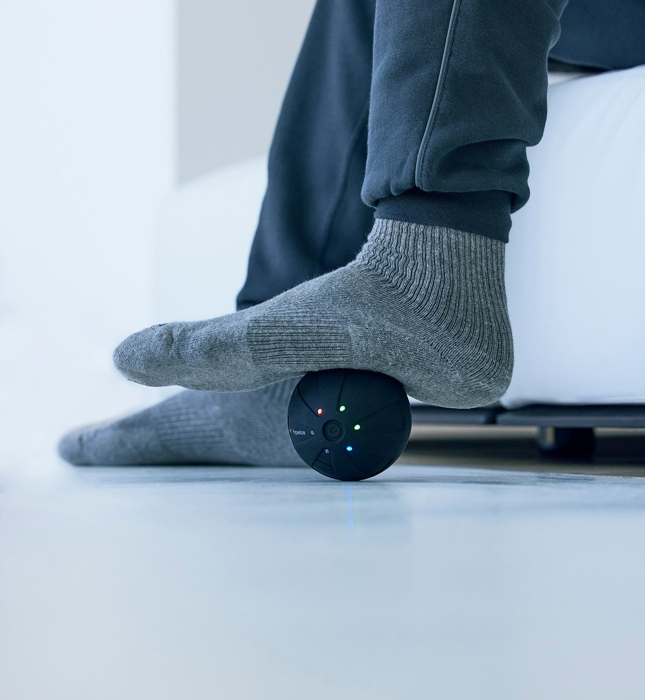close up shot of a person using a hypersphere go massager on their foot a white surface