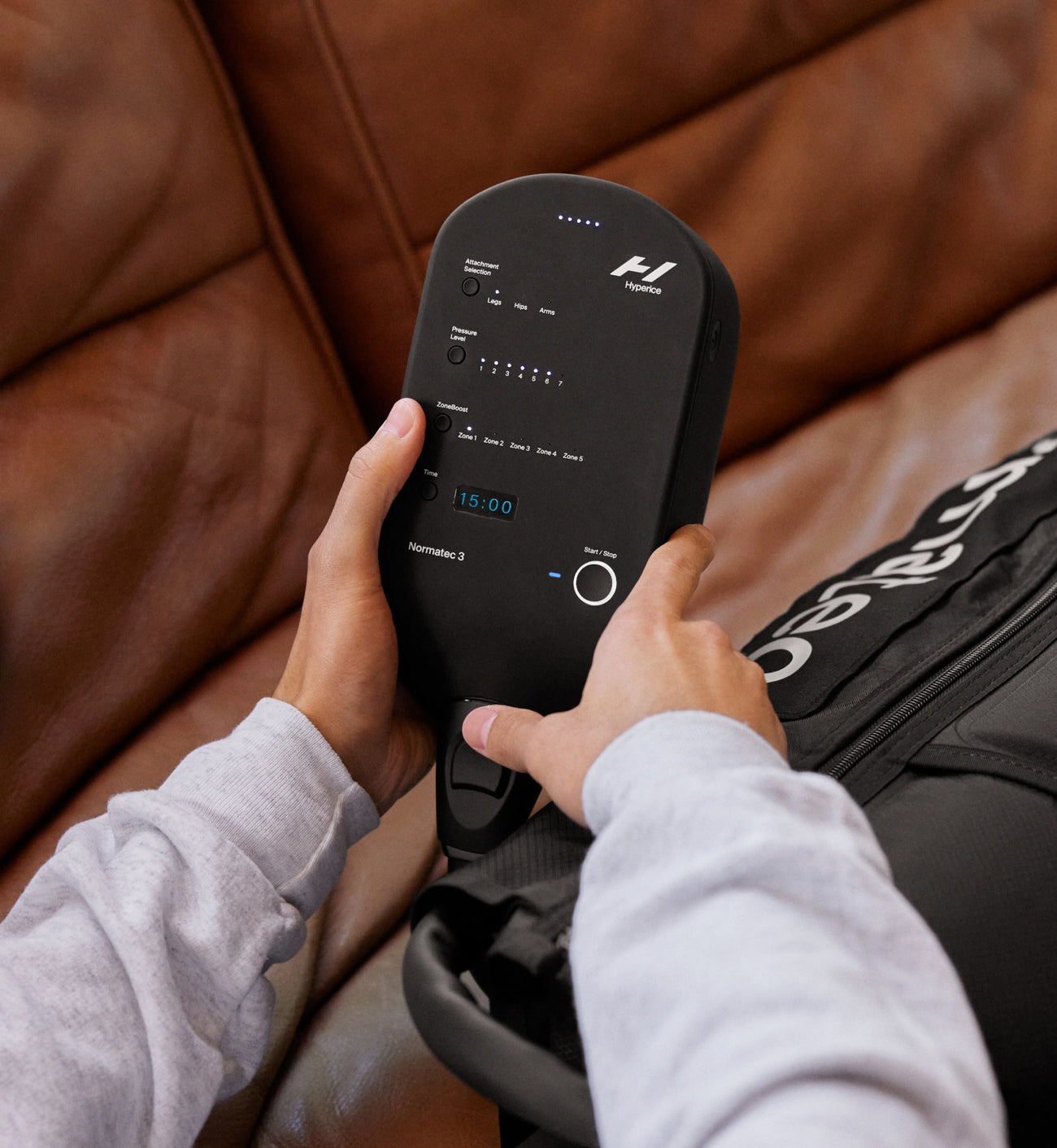 close up of a person holding the control unit of the normatec 3 legs 