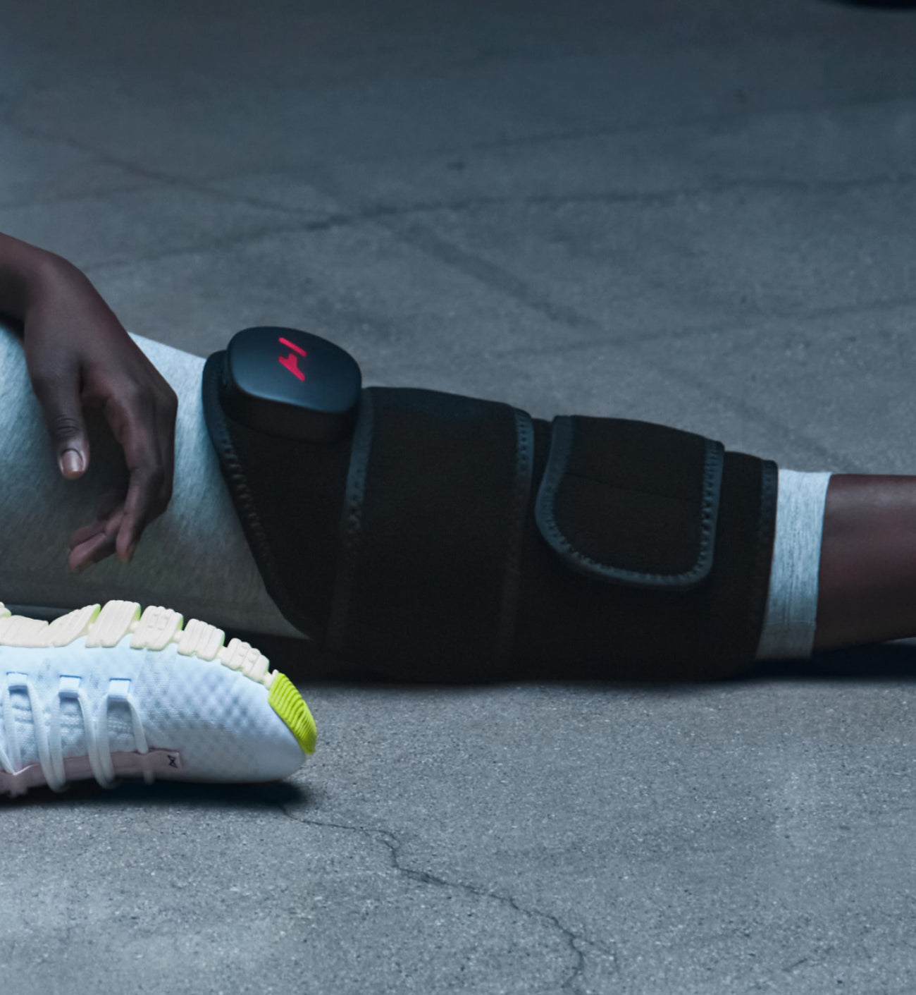 Person sitting down wearing a venom 2 leg massage device on their leg with a gray background