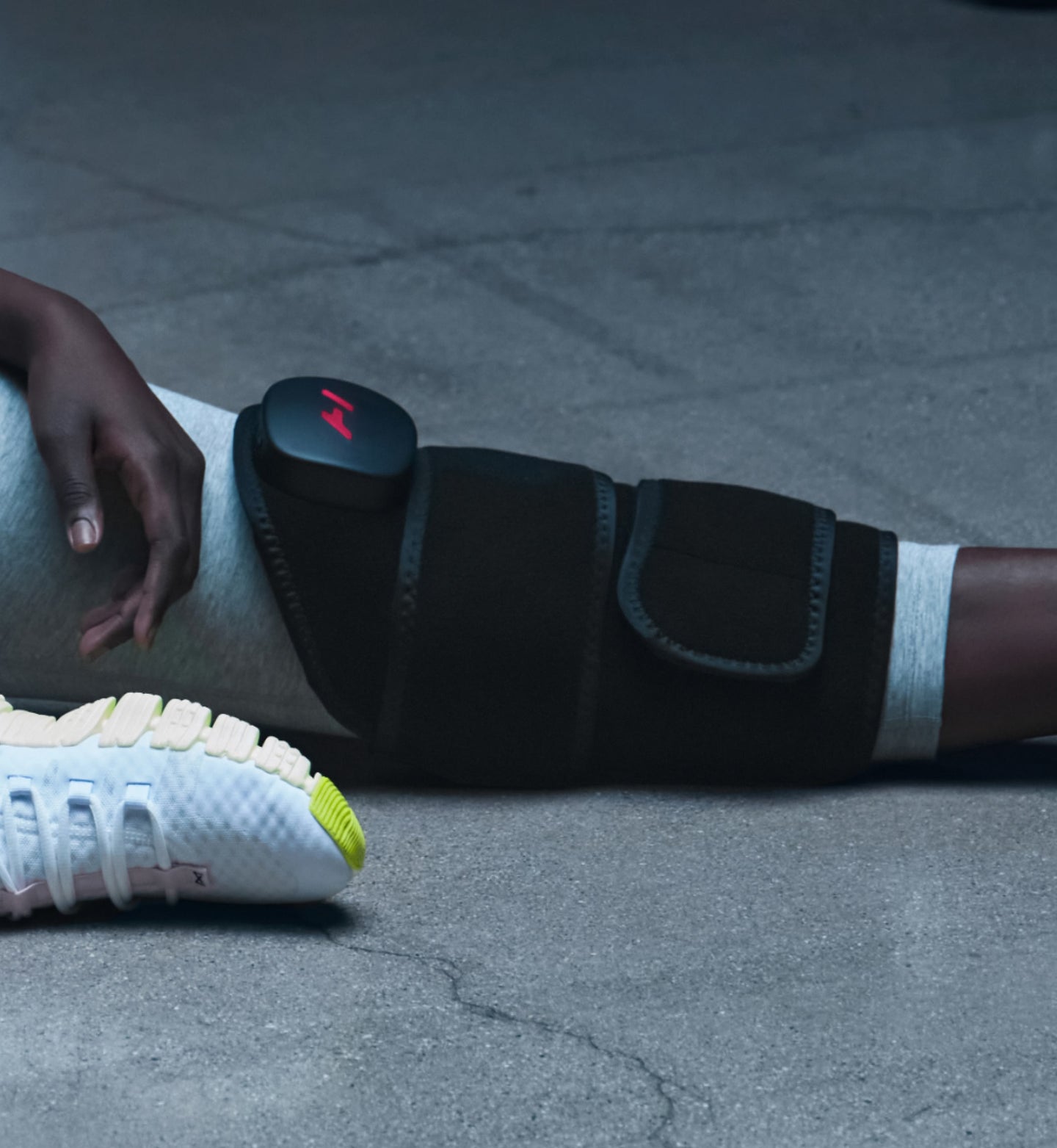 Person sitting down wearing a venom 2 leg massage device on their leg with a gray background