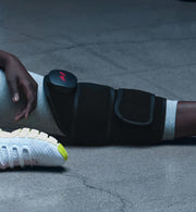 Person sitting down wearing a venom 2 leg massage device on their leg with a gray background